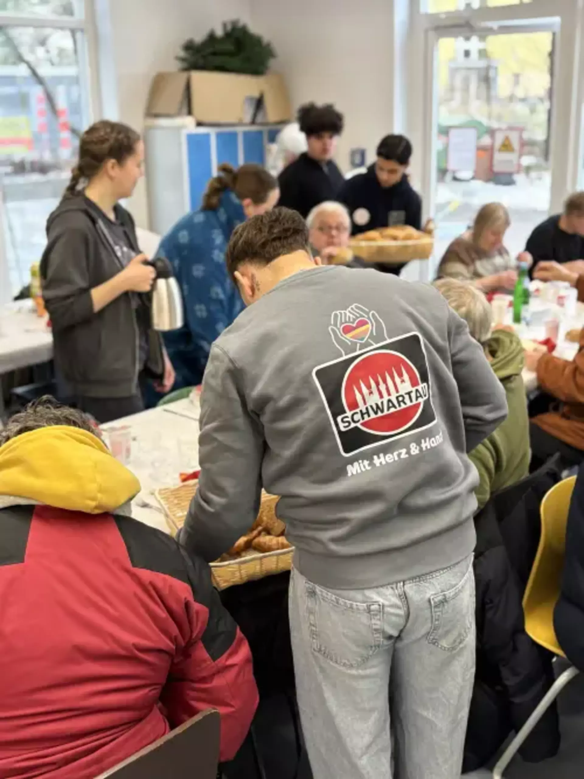 Eine Kollege serviert Brötchen an Besucher*innen.
