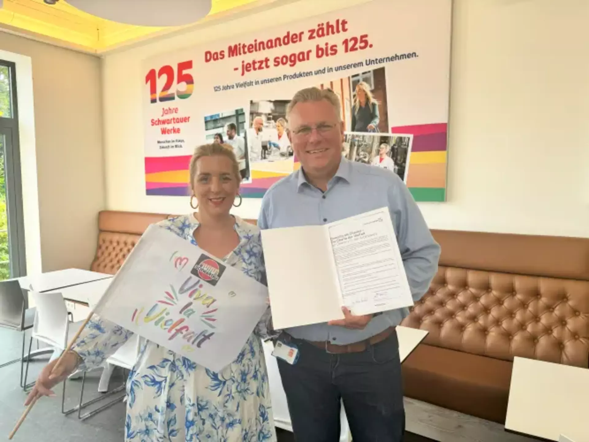 Zwei Personen mit der Urkunde zur Unterzeichnung der Charta der Vielfalt.