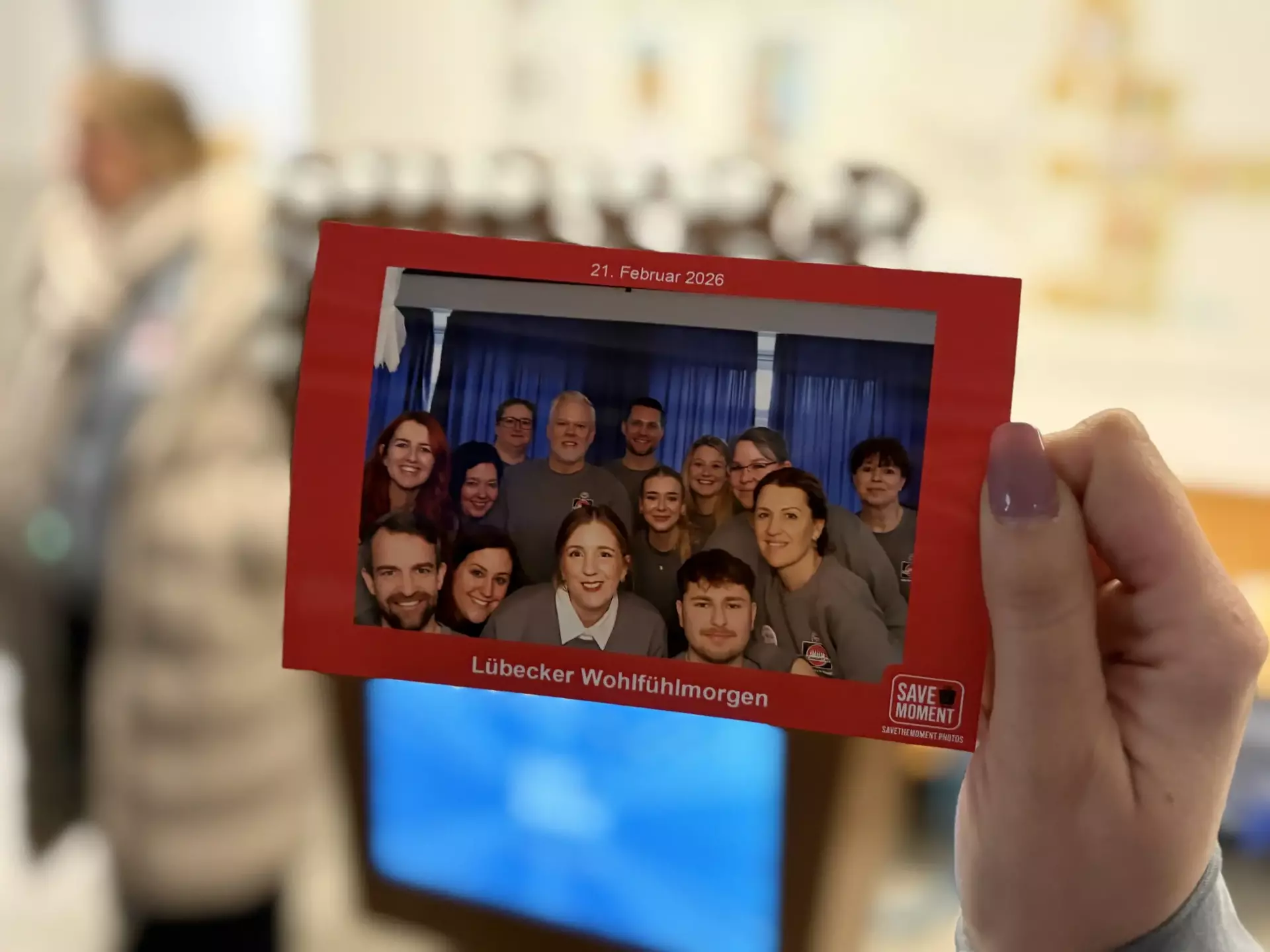Eine Hand hält das ausgedruckte Gruppenfoto aus einer Fotobox.