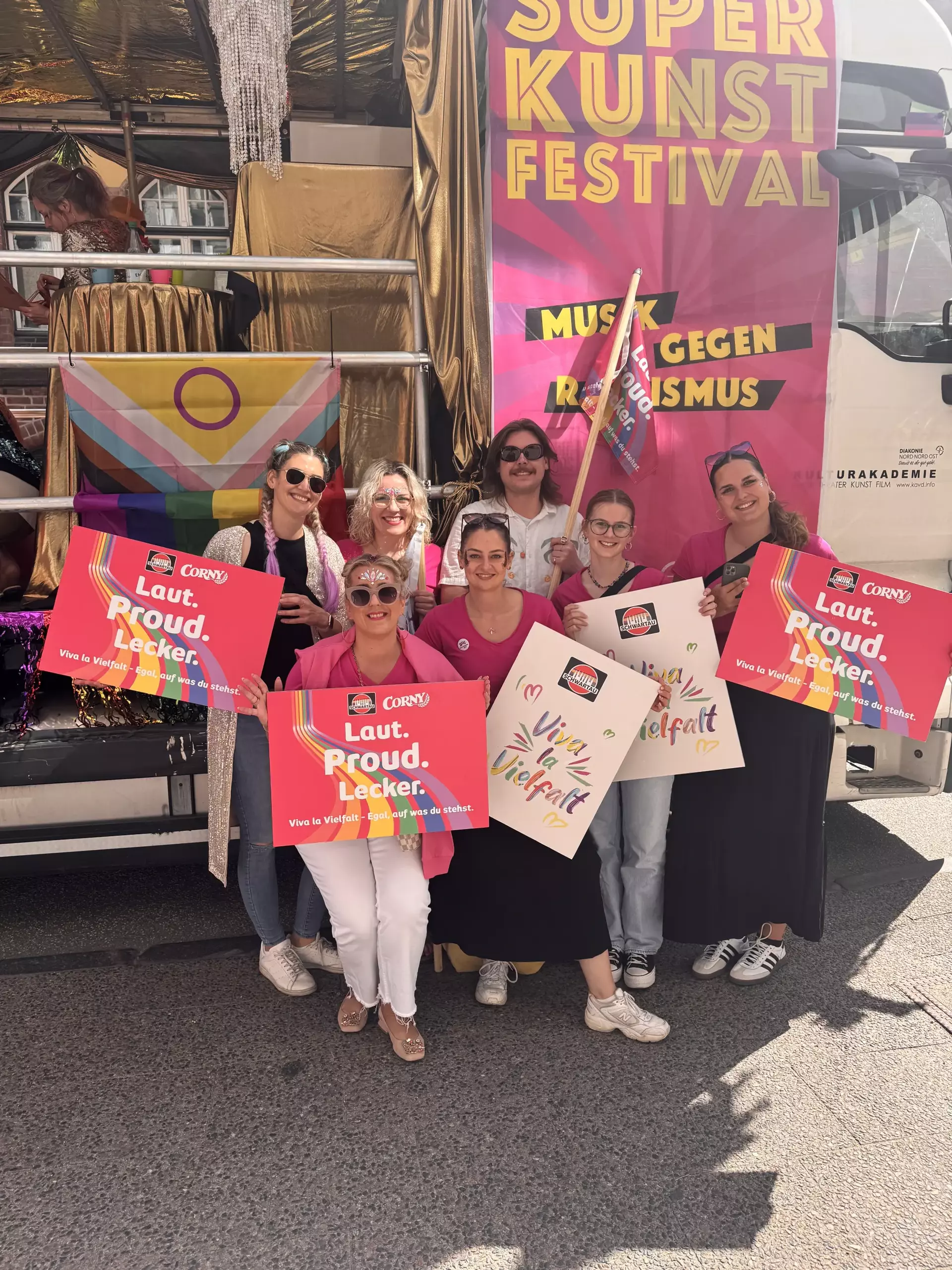 Personen aus Team Schwartau mit bunten Schildern vor einem Truck beim Lübecker CSD