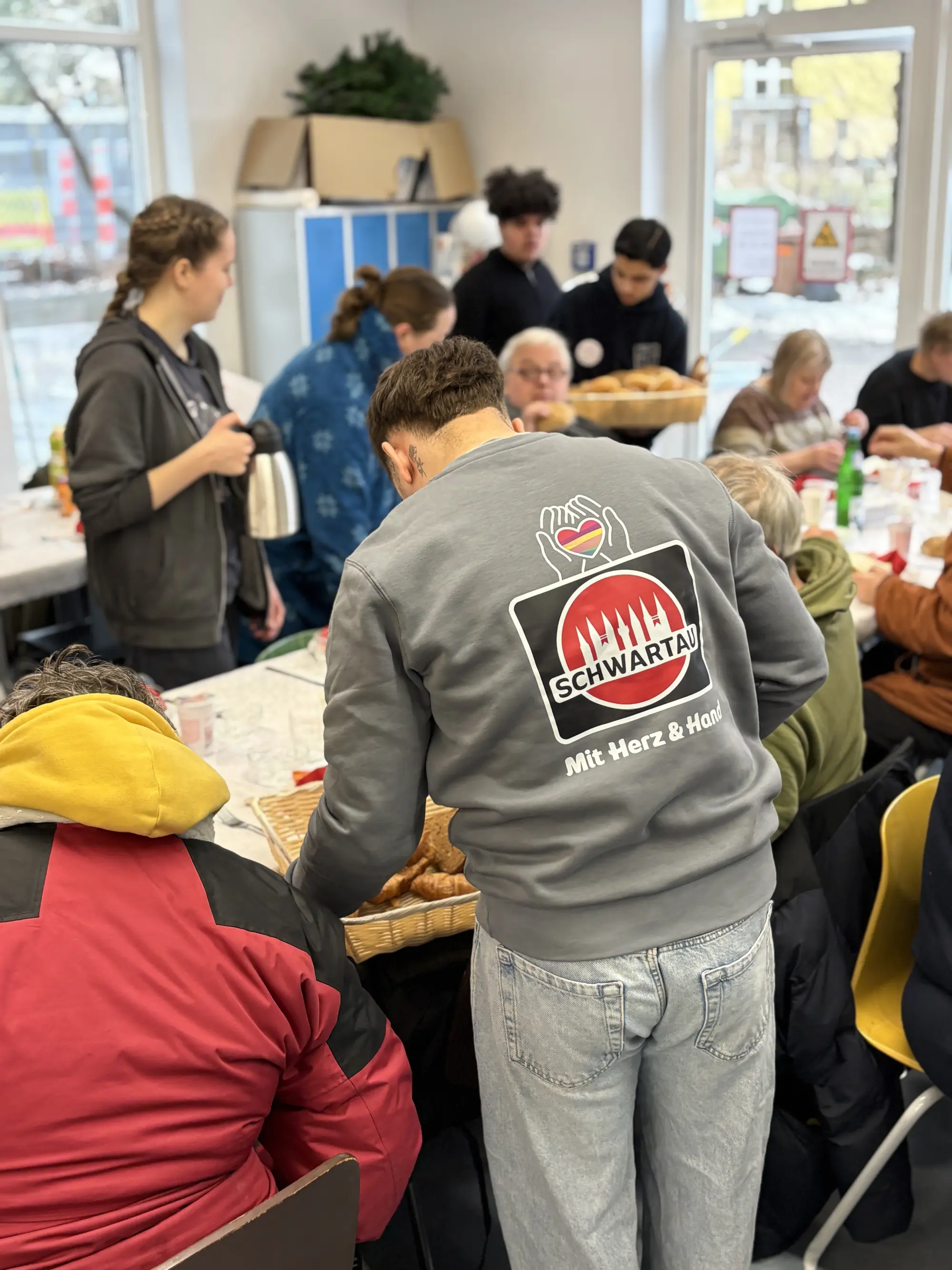 Eine Kollege serviert Brötchen an Besucher*innen.