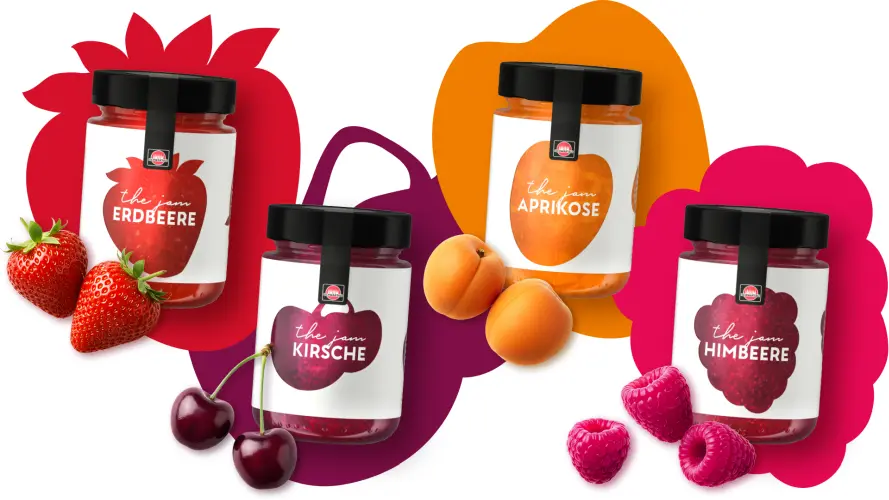 Vier Sorten der Schwartau Produktlinie „the jam“: Erdbeere, Kirsche, Aprikose und Himbeere. Die Fruchtaufstriche stehen vor grafischen Fruchtsilhouetten in den jeweiligen Sortenfarben, ergänzt durch frische Erdbeeren, Kirschen, Aprikosen und Himbeeren.